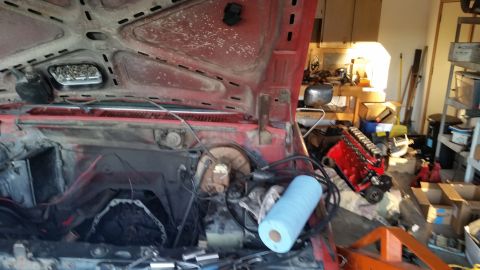 1981 Ford Bronco - The engine bay of a vehicle is shown with the hood open, revealing engine parts and a roll of blue paper towels on the side.