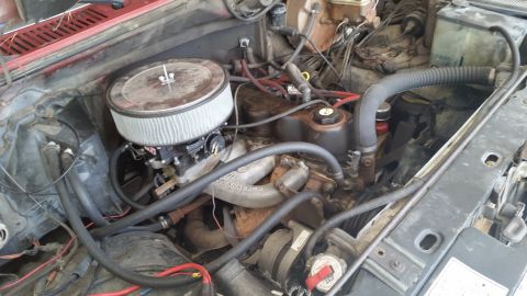 1981 Ford Bronco - The engine bay of a vehicle, showing the air filter, carburetor, and various hoses and wiring.