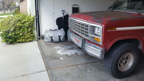 1981 Ford Bronco - Front view of a red Ford pickup truck with a chrome bumper and grille, parked in a garage.