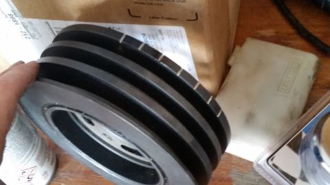 1981 Ford Bronco - Close-up of a multi-groove pulley, likely a replacement part, with other items in the background.