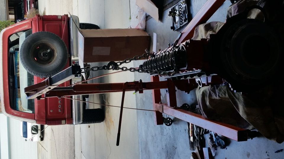 red pickup truck with spare tire on back, engine being lifted out by hoist
