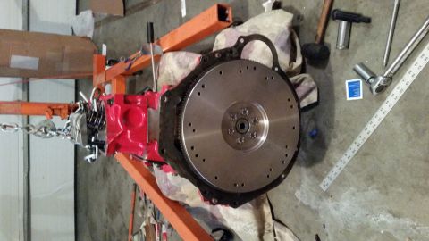 1981 Ford Bronco - Engine block and flywheel assembly, supported by an engine stand, with various tools laid out on the floor.