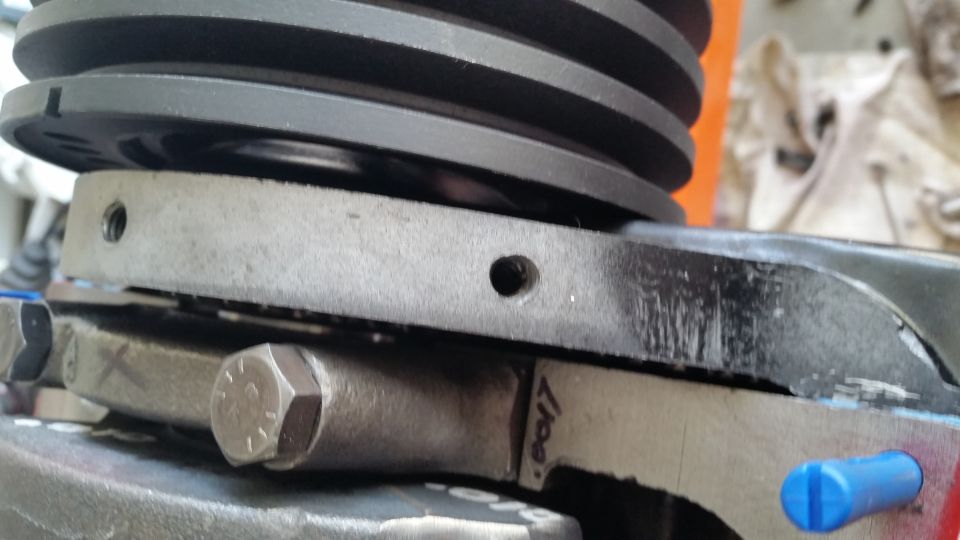 Close-up of engine pulley and connecting rod assembly with visible bolts and markings