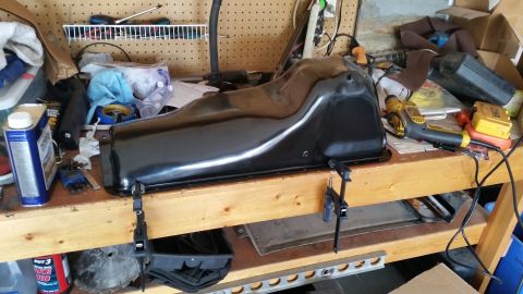 1981 Ford Bronco - A black oil pan is secured with clamps on a wooden workbench, surrounded by various garage items.