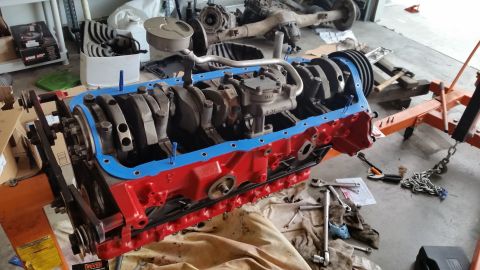 1981 Ford Bronco - Engine block assembly with crankshaft and oil pan gasket, supported by an engine stand in a garage.