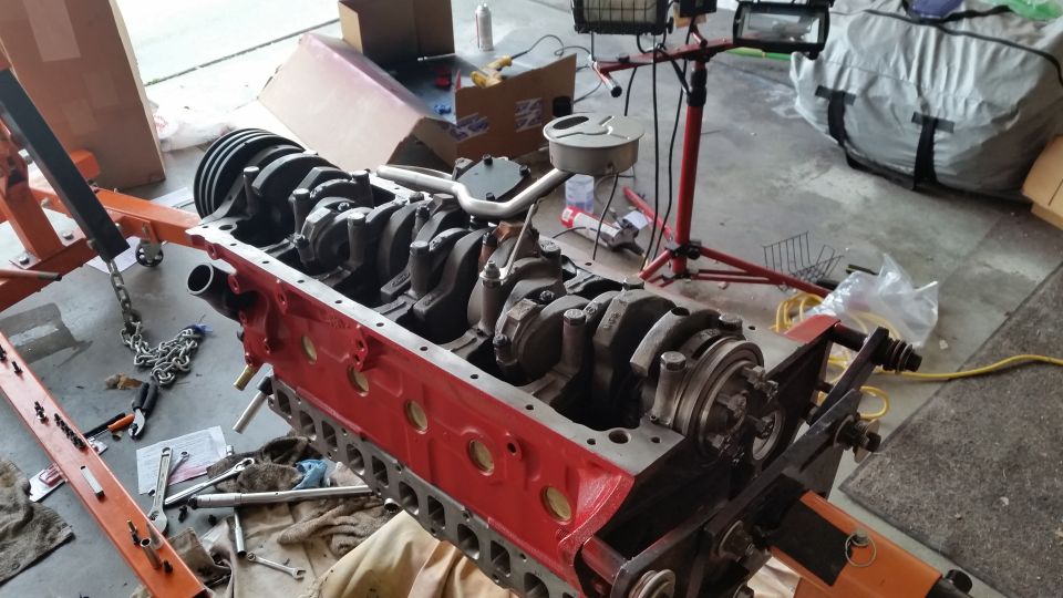 Engine block on an orange engine stand, with crankshaft visible inside