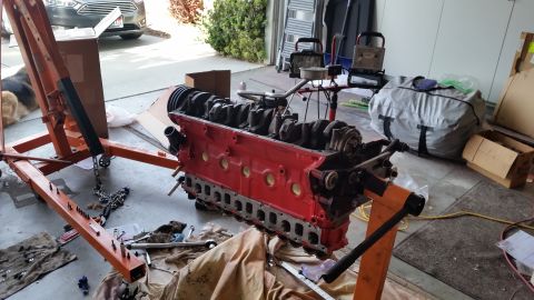 1981 Ford Bronco - A red V8 engine is disassembled and resting on an engine stand in a garage setting.