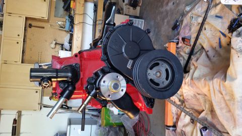 1981 Ford Bronco - A red engine block with black accessories, including a pulley and power steering pump, is shown in a workshop setting.