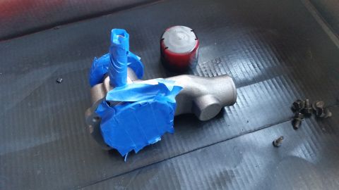 1981 Ford Bronco - A brake master cylinder is prepared for painting with blue masking tape covering its ports.
