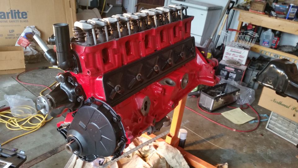Red V8 engine with black valve covers on an orange engine stand, viewed from the front-left