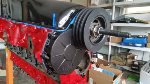 1981 Ford Bronco - Close-up view of a red engine block a crankshaft pulley and a black timing cover.