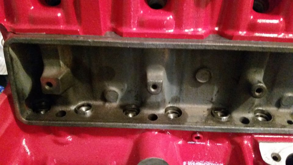 Red engine block with visible cylinder bores and bolt holes