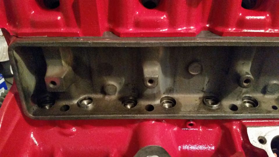 Close-up of a red engine block with a gray cylinder head bolted on