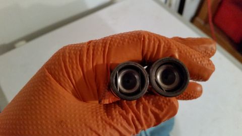 1981 Ford Bronco - Two valve keepers are held in an orange gloved hand.