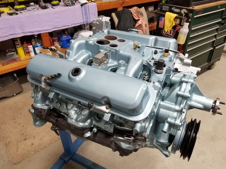 V8 engine on stand, light blue paint, some parts attached like intake manifold and valve covers. Supermotors.net logo visible