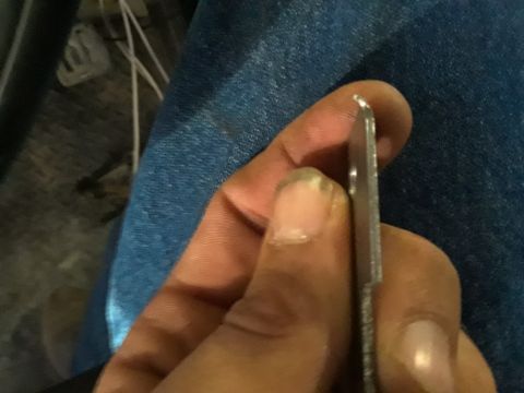 1985 Ford Bronco - A person is holding a thin metal object, possibly a tool or a car part, against a blue fabric background.