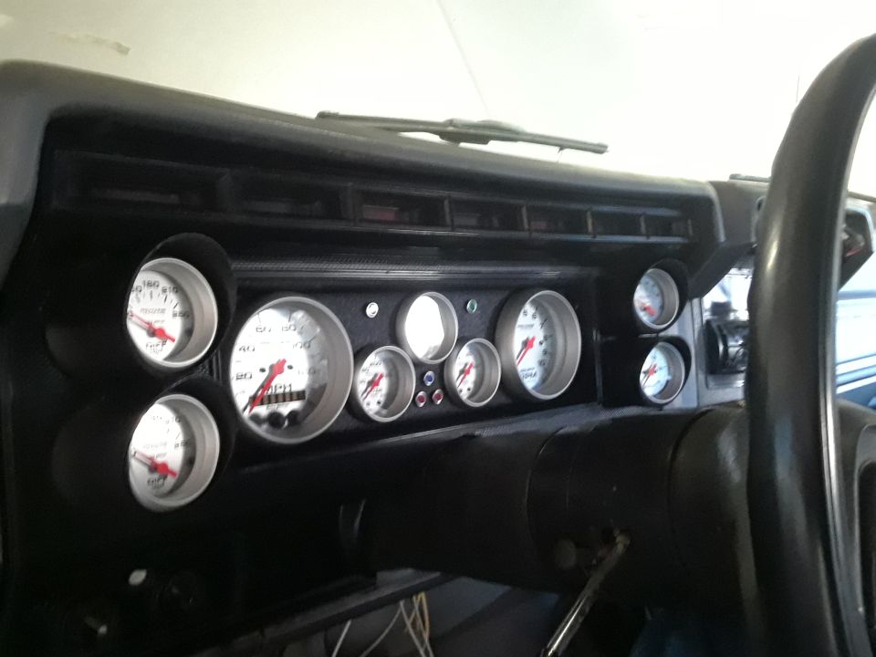 Vehicle dashboard with multiple gauges and steering wheel.