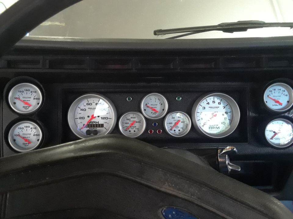 Vehicle dashboard with multiple gauges including speedometer, tachometer, fuel, oil, water temp, and voltage.