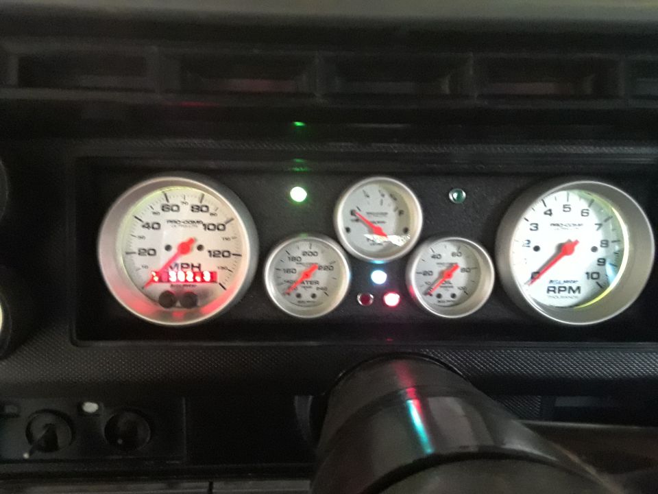 Vehicle dashboard with multiple Pro-Comp gauges: speedometer, tachometer, oil pressure, water temperature.