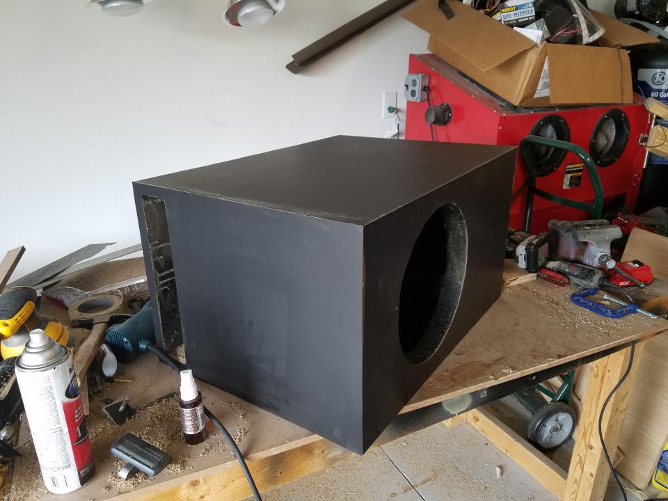 Photo of a black-finished ported subwoofer box on a workbench