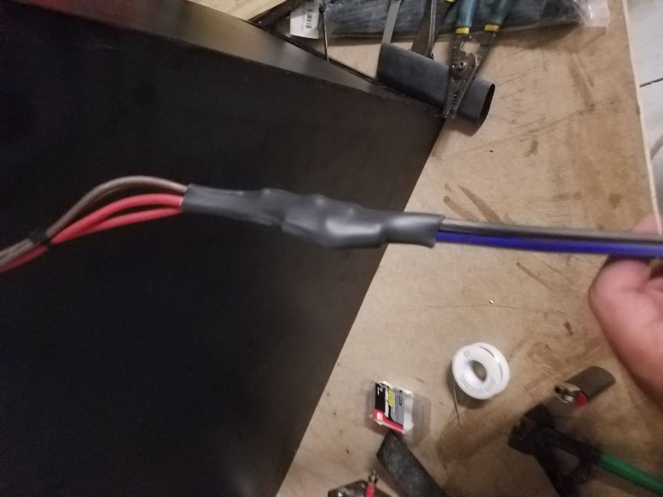 Photo of power and speaker wires with heat-shrink tubing on a workbench