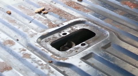 1994 Ford Bronco - Photograph of a recessed pocket in a sheet-metal truck bed floor, not a technical document.