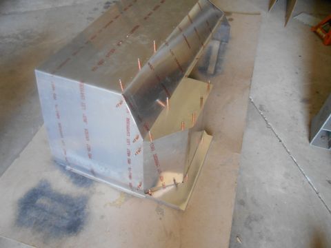 1992 Ford Bronco - A partially assembled metal component, possibly part of a larger structure, is shown resting on a cardboard surface. The metal has red text…