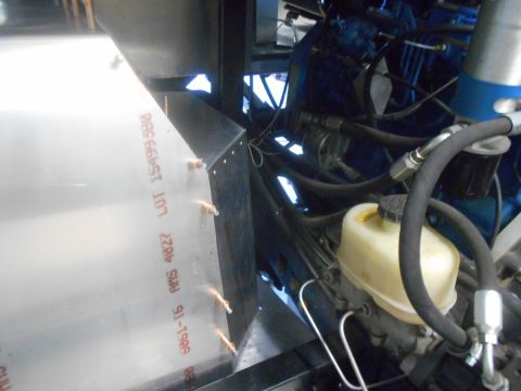 1992 Ford Bronco - A close-up view of a shiny metal panel with orange text indicating material specifications and lot numbers, attached to a vehicle's engine…