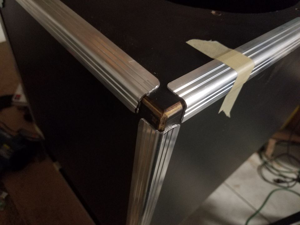 close-up of aluminum trim on black speaker cabinet corner, taped in place