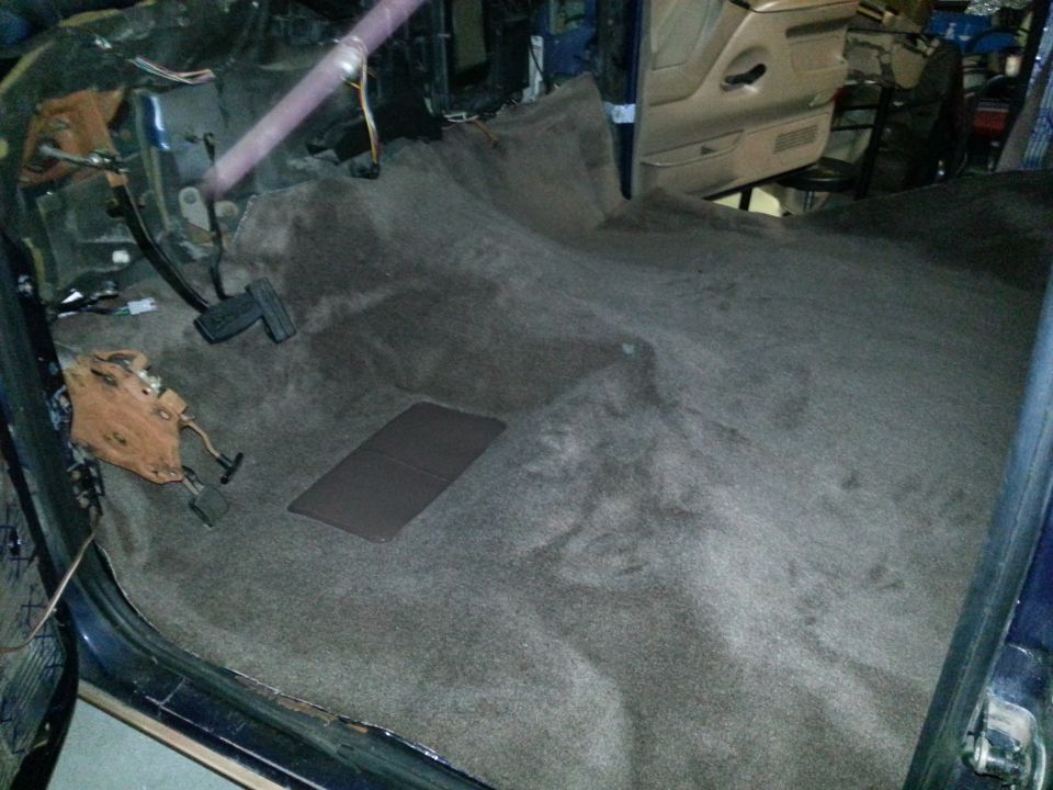 Carpeted truck cab floor with pedals and wiring visible during interior work