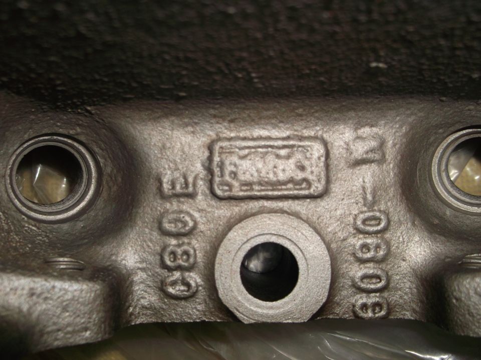Close-up of cast iron engine block with casting marks and numbers "E380" and "1-0808".