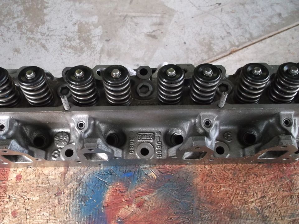 Gray V8 engine cylinder head with valve springs and retainers.