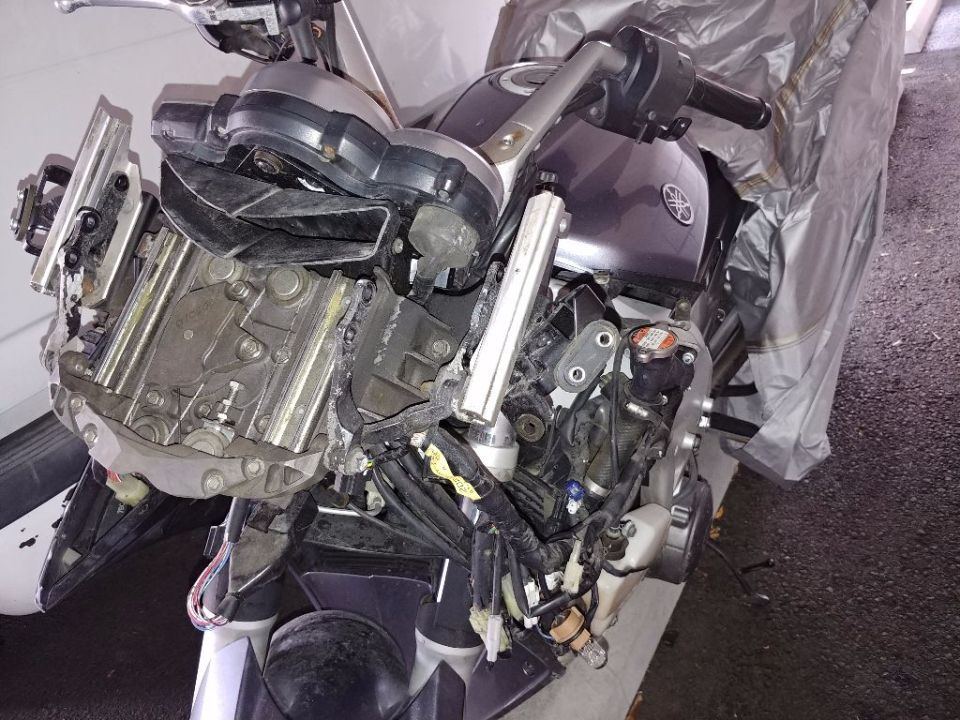 Damaged front end of a Yamaha motorcycle with exposed engine and wiring.
