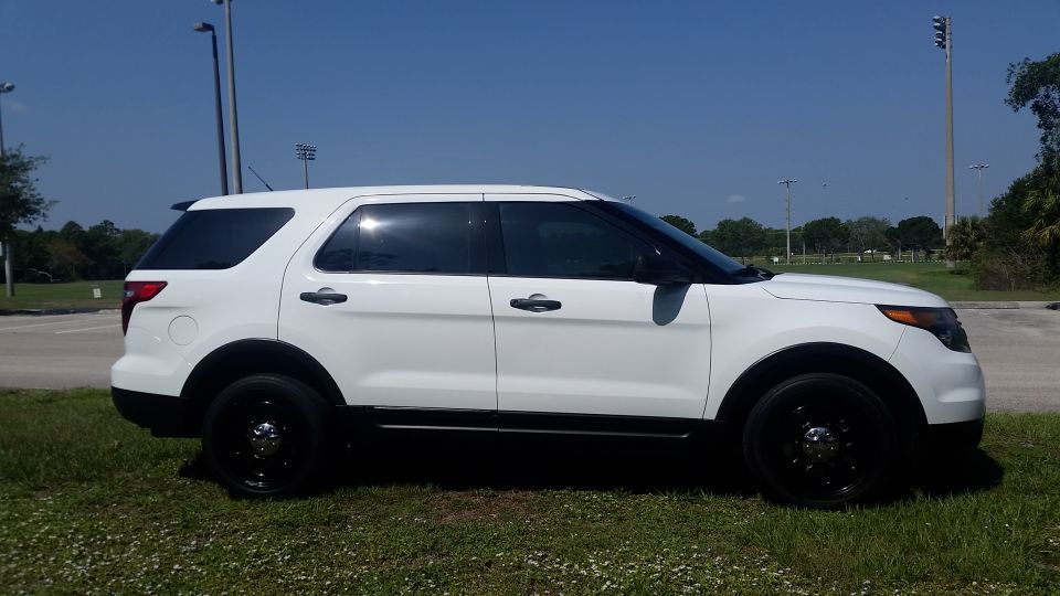 White 2013 Ford Explorer side view, parked on grass.
