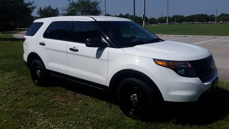 White 2013 Ford Explorer SUV parked on grass, front 3/4 view.