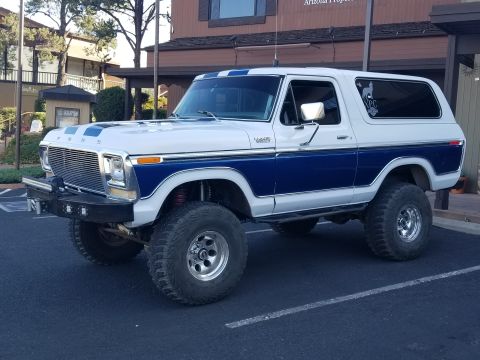 1995 Ford Bronco - A lifted 1978-1979 Ford Bronco with a blue and white two-tone paint scheme and racing stripes on the hood is parked in a parking lot.
