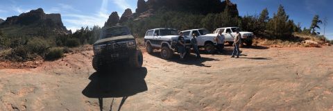 1995 Ford Bronco - A group of four people stand around three SUVs and one pickup truck parked on a rocky, desert landscape with red rock formations in the bac…