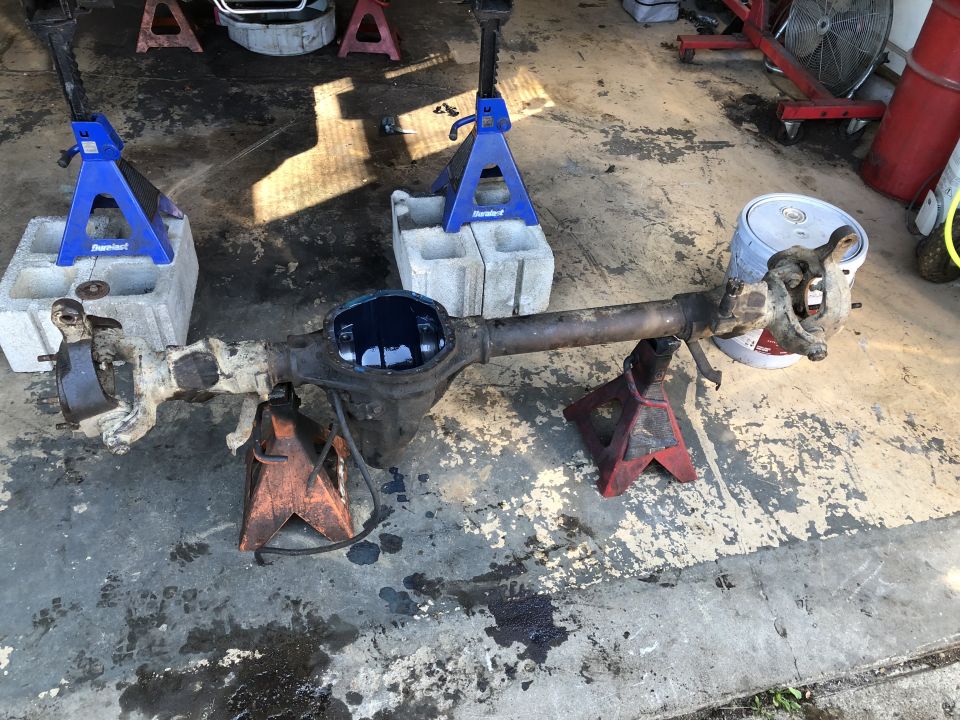 Disassembled rear axle assembly on jack stands, differential cover removed.