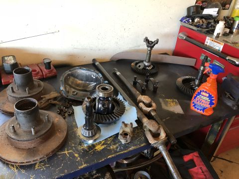 1995 Ford F-150 - A collection of automotive differential and axle parts are laid out on a workbench. Visible parts include differential gears, a differentia…