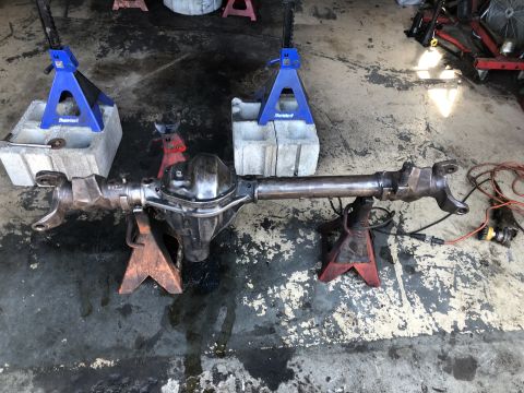 1995 Ford F-150 - A rear axle assembly is supported by jack stands on a concrete floor. The axle appears to be from a Ford F-150, given the context provided.