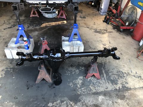 1995 Ford F-150 - A freshly painted black Ford F-150 rear axle assembly is supported by jack stands on a concrete floor. The vehicle frame is visible in the…