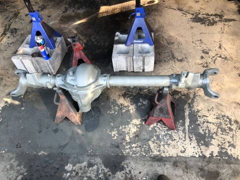 1995 Ford F-150 - A silver-painted Ford F-150 rear axle assembly is supported by two red jack stands on a concrete floor. A blue and red spray can rests on c…