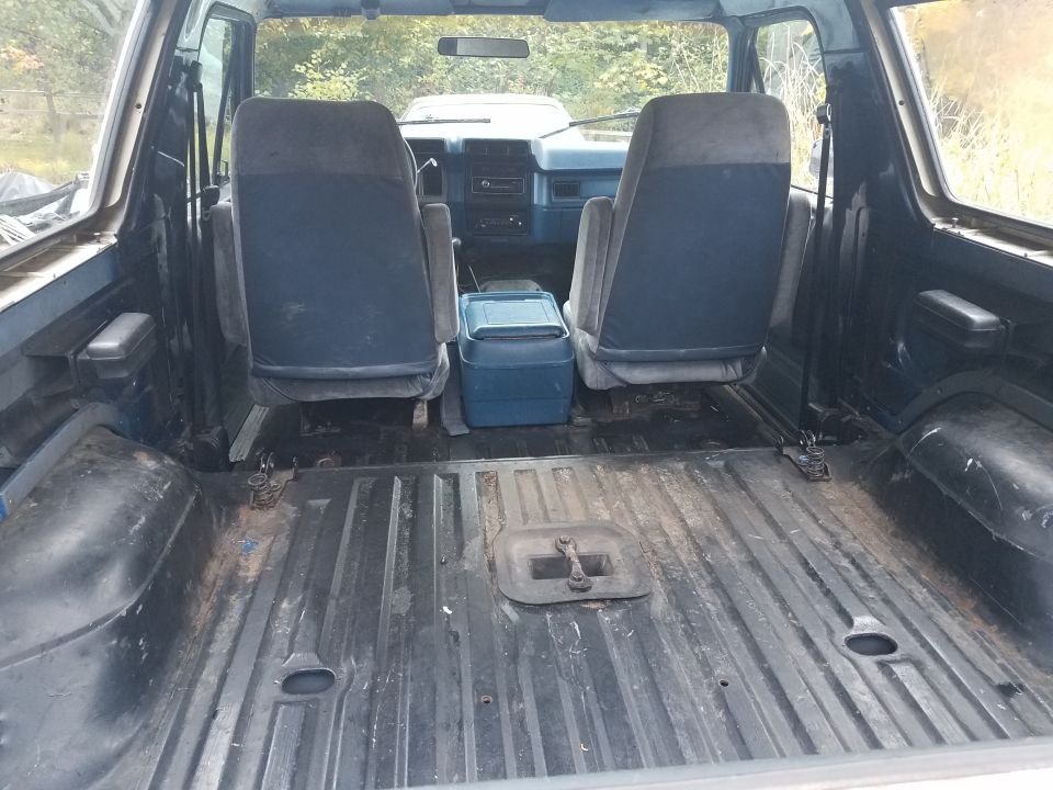 Interior of a vintage Ford Bronco showing the rear cargo area and front seats.
