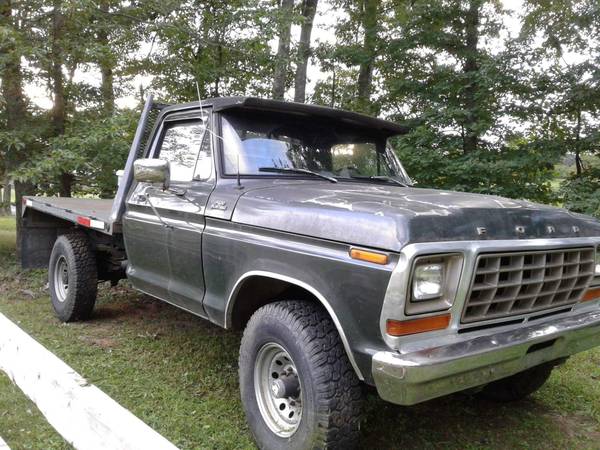 1979 Ford F-250 pickup truck, front driver's side view, parked on grass with trees.