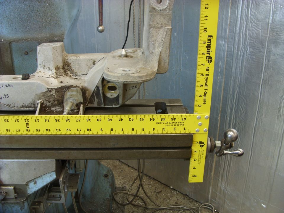 Close-up of a metal machine part with a yellow ruler showing inches and centimeters.