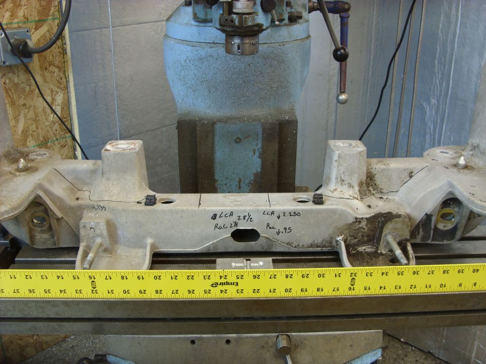 Cast aluminum part with markings being measured by a yellow tape measure.