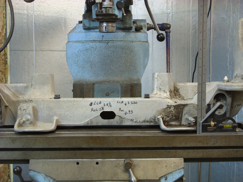 Close-up of a metal part with handwritten measurements on it, sitting on a machine tool