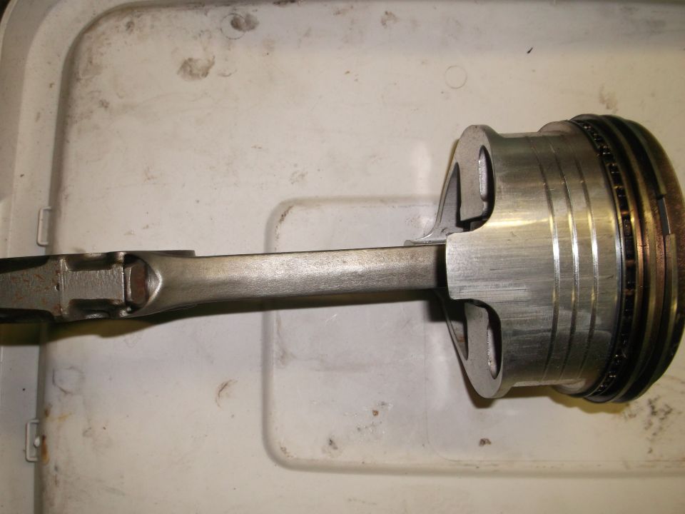 Piston and connecting rod assembly with wear marks on the piston skirt and rings