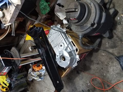 1996 Ford Bronco - A transfer case and a black metal bracket are stored in a cluttered garage with various tools and equipment.