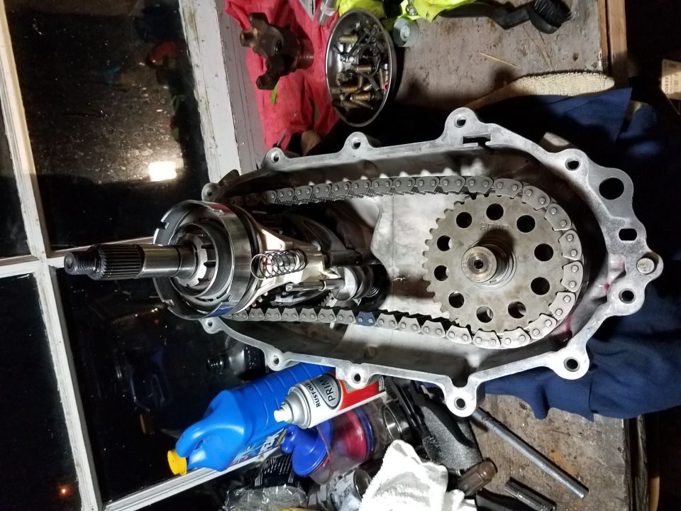 transfer case with chain and gears exposed, some tools and fluids nearby